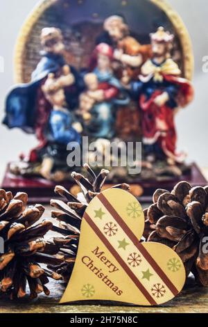 Composizione natalizia con cuore giocattolo. Nel cuore giocattolo in primo piano con l'iscrizione 'buon Natale' e coni di pino. Primo piano. Immagine sfocata di na Foto Stock