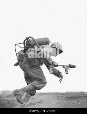 IWO JIMA, OCEANO PACIFICO - Febbraio 1945 - un operatore di flametrower di Co. E, 2a BN, 9 Marines, corre sotto fuoco durante la parte iniziale della Battaglia Foto Stock