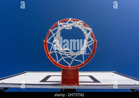 un primo piano di un cerchio di basket glassato arancione contro il cielo blu Foto Stock