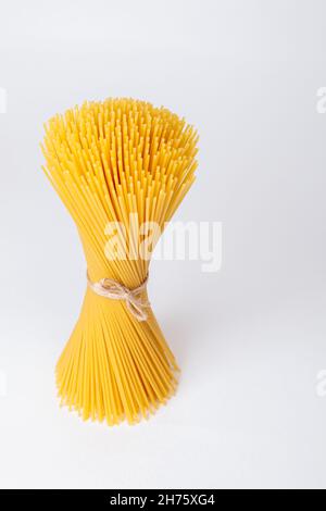 Un mazzo verticale, un mazzo di spaghetti crudi legati con corda. Fascio su sfondo bianco. Cucina italiana. Foto Stock