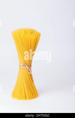 Un mazzo verticale, un mazzo di spaghetti crudi legati con corda. Fascio su sfondo bianco. Cucina italiana. Foto Stock