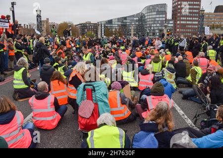 Londra, Regno Unito. 20 Nov 2021. I manifestanti siedono e bloccano Lambeth Bridge durante la dimostrazione insulata della Gran Bretagna.i manifestanti marciarono attraverso Londra per protestare contro il recente incarcerazione di nove attivisti insulati della Gran Bretagna. Gli attivisti chiedono che il governo isoli tutte le abitazioni sociali entro il 2025, e si assuma la responsabilità di garantire che tutte le case nel Regno Unito siano più efficienti dal punto di vista energetico entro il 2030, come parte dei più ampi obiettivi di cambiamento climatico e decarbonizzazione. Credit: SOPA Images Limited/Alamy Live News Foto Stock