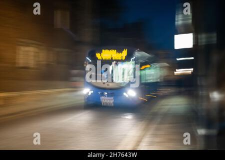 Cambridge, Cambridgeshire, Regno Unito – Novembre 16 2021. Autobus notturno che attraversa la città di Cambridge. Catturato con una velocità dell'otturatore ridotta per un movimento deliberato Foto Stock