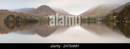 Un'autunnale riflessione panoramica di Grasmere e le campane circostanti in un'atmosfera giornata di nube bassa nel Parco Nazionale del Distretto dei Laghi. Foto Stock