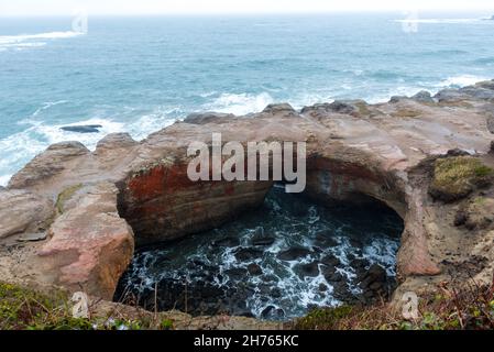 Diavoli punchbowl arco sulla riva della costa dell'Oregon Foto Stock