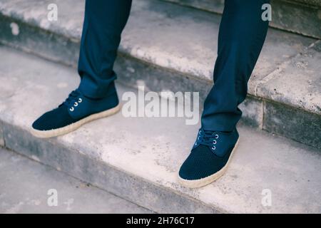 Stucco i piedi in pantaloni e sneakers su gradini di pietra Foto Stock