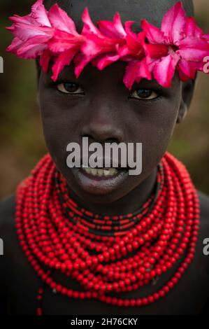 Giovane ragazzo della tribù Karo che indossa perle e fiori Foto Stock