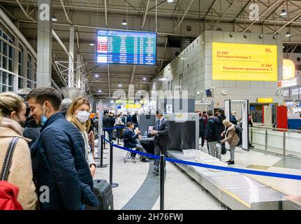 I passeggeri in maschere facciali in attesa in coda forsSacchi bagagli di sicurezza si trovano all'ingresso del terminal dell'aeroporto di Almaty, Kazakhstan Foto Stock