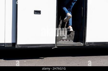 Le gambe del turista in jeans e snickers come lui a bordo dell'autobus attraverso le scale laterali Foto Stock