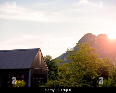 La cabina nera è casa nel verde parco vicino alla montagna in fondo cielo mattina con la luce del sole. Foto Stock