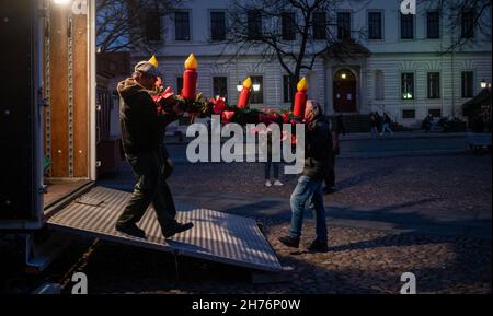 20 novembre 2021, bassa Sassonia, Lüneburg: Showmen ha istituito il mercato di Natale sulla piazza del municipio. L'odore di bratwurst e mandorle dovrebbe attirare i visitatori nella città vecchia di Lüneburg da mercoledì (24 novembre) in poi. Con la costruzione delle bancarelle, la città anseatica vuole implementare il concetto di città di Natale di Lüneburg. Deve essere applicata la regola 2G. Foto: Philipp Schulze/dpa Foto Stock