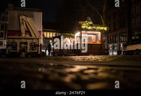 20 novembre 2021, bassa Sassonia, Lüneburg: Showmen ha allestito uno stand per il mercato di Natale sulla piazza del municipio. L'odore di bratwurst e mandorle dovrebbe attirare i visitatori nella città vecchia di Lüneburg da mercoledì (24 novembre) in poi. Allestendo le bancarelle, la città anseatica vuole implementare il concetto di Lüneburg come città di Natale. Deve essere applicata la regola 2G. Foto: Philipp Schulze/dpa Foto Stock