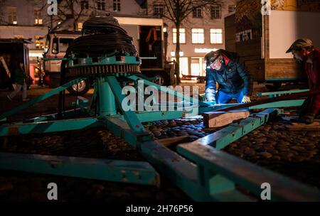 20 novembre 2021, bassa Sassonia, Lüneburg: Showmen stanno allestendo un carosello per il mercato di Natale sulla piazza del municipio. L'odore di bratwurst e mandorle dovrebbe attirare i visitatori nella città vecchia di Lüneburg da mercoledì (24 novembre) in poi. Allestendo le bancarelle, la città anseatica vuole implementare il concetto di Lüneburg come città di Natale. Deve essere applicata la regola 2G. Foto: Philipp Schulze/dpa Foto Stock