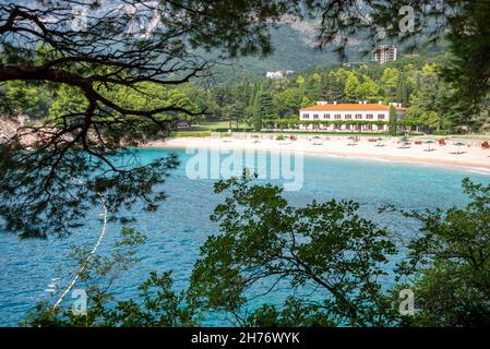 Bei sentieri alberati che corrono a nord da Sveti Stefan Island, oltre il mare blu e le località turistiche, punteggiato lungo la costa adriatica. Foto Stock