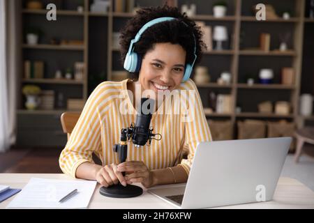 Felice giovane donna nera in cuffie e registrazione microfono professionale Foto Stock