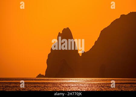 Un tramonto dorato ardente con la silhouette di un capo roccioso sul mare. Spazio di copia. Nessuno. Concetto di vacanza, vacanza e viaggio Foto Stock