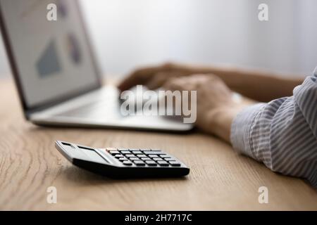 Primo piano focus su calcolatrice, mani femminili sulla tastiera del laptop Foto Stock