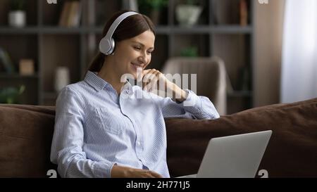 Donna in cuffia utilizza un notebook per guardare film o webinar didattico Foto Stock