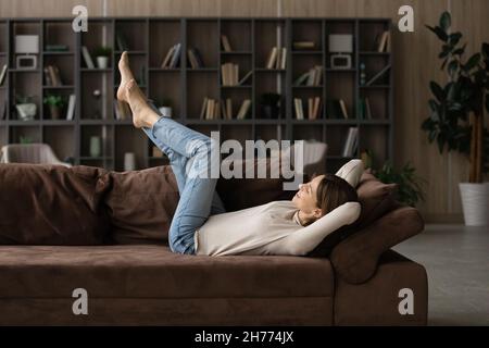 Donna spensierata sdraiata sul divano con le gambe sollevate Foto Stock