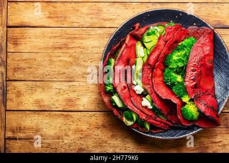 Frittelle di barbabietole farcite con verdure su tavola rustica in legno. Cibo sano. Spazio per il testo Foto Stock