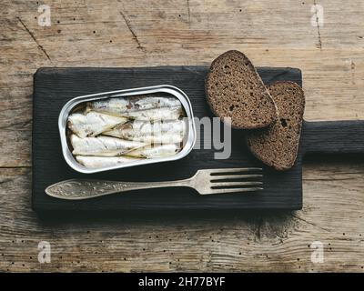 le sardine aperte possono su vecchio tavolo da cucina in legno, vista dall'alto Foto Stock