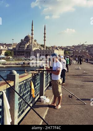 Vita quotidiana a Istanbul pescatori sul ponte Galata sullo sfondo Yeni Moschea, Turchia Foto Stock