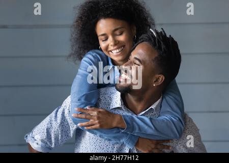 Felice giovane uomo di etnia brasiliana che dà cavalcata di piggyback alla moglie. Foto Stock