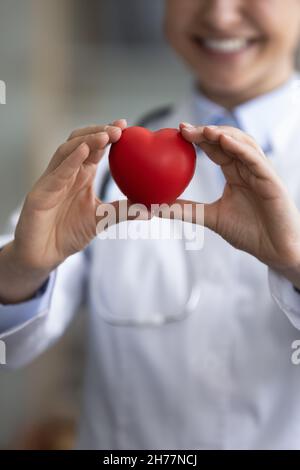 Verticale primo piano sorridente medico indiano donna tenendo il cuore Foto Stock