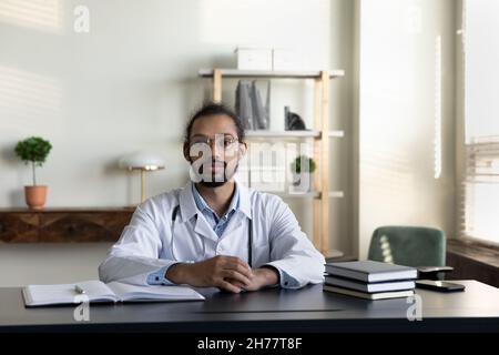 Ritratto medico afroamericano in bicchieri seduti alla scrivania Foto Stock