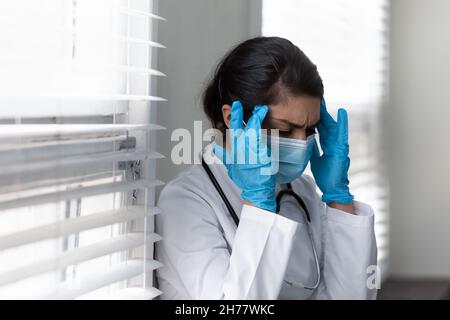 Primo piano su medico donna indiana stanca in maschera medica Foto Stock