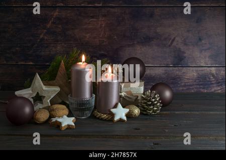 Decorazione di Natale in rosa scuro e marrone con candele palle, coni e stelle contro un rustico sfondo di legno, spazio copia, fuoco selezionato, stretto Foto Stock