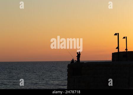 Tramonto mediterraneo fotografato alla silhouette di Acre Israel di pesca ragazzi locali Foto Stock