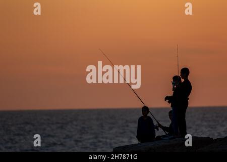 Tramonto mediterraneo fotografato alla silhouette di Acre Israel di pesca ragazzi locali Foto Stock