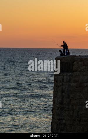 Tramonto mediterraneo fotografato alla silhouette di Acre Israel di pesca ragazzi locali Foto Stock