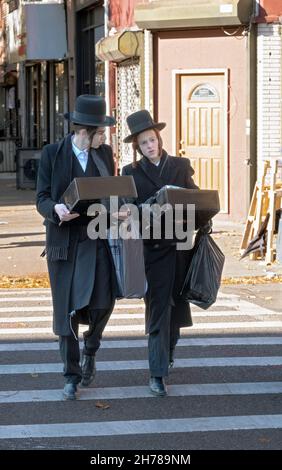Due ebrei ortodossi hasidici che camminano sulle scatole di trasporto di Lee Ave. venerdì pomeriggio a Williamsburg, Brooklyn, New York. Foto Stock