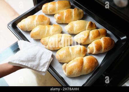 Una donna toglie le focaccine dal forno su una teglia da forno Foto Stock