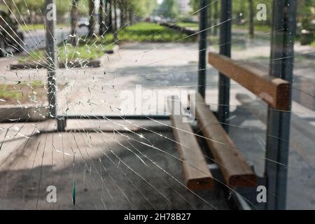 Il banco si trova dietro il vetro rotto della fermata dell'autobus Foto Stock