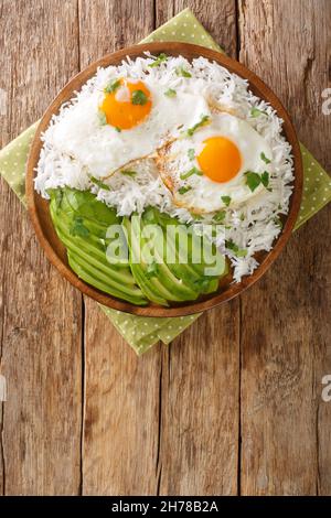 Ecuadoriana colazione semplice di riso bollito e uova fritte primo piano in un piatto sul tavolo. Vista verticale dall'alto Foto Stock