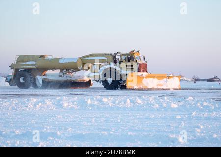 Pulizia aeroporto dalla neve durante la tempesta di neve. Pulizia pista dalla neve. Sgombrare la neve con i bulldozer dai grembiuli dell'aeroporto. Foto Stock