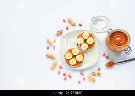 Due panini con burro di arachidi e banana su piatto bianco. Sana colazione vegana. Vista dall'alto, disposizione piatta, spazio di copia. Foto Stock