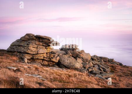 Sopra un mare di nuvole sulla cima del Monte Brocken nei monti Harz, Parco Nazionale Harz, Sassonia-Anhalt, Germania. Cielo rosa al tramonto e formazioni rocciose. Foto Stock
