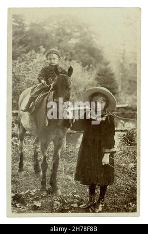 Cartolina originale dei primi anni del 1900 di ragazzino seduto su un cavallo, con la sorella che tiene le redini, Llandygwydd, Cardiganshire, Galles, Regno Unito circa 1909 Foto Stock