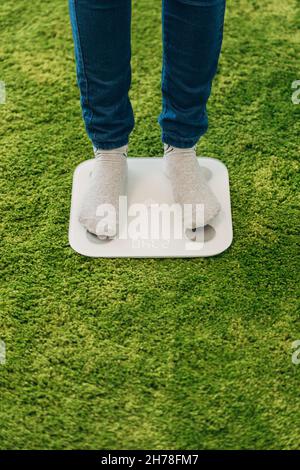 La ragazza misura il peso sulle bilance intelligenti Foto Stock