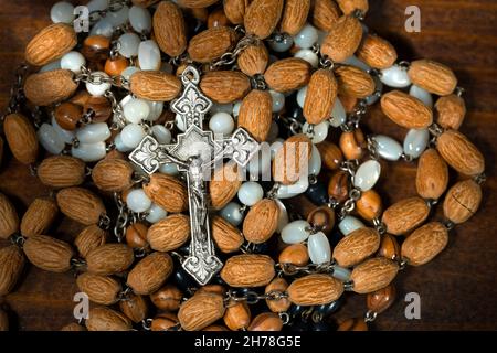 Dettaglio di un vecchio crocifisso d'argento con molte perle rosarie su sfondo di legno Foto Stock