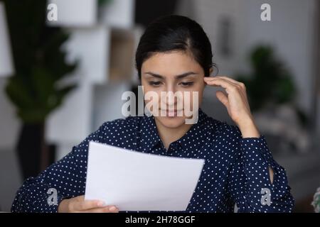 Concentrato giovane donna d'affari indiana intelligente analisi documento cartaceo. Foto Stock