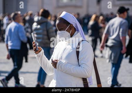 VATICANO ROMA, 21 NOVEMBRE 2021. Una suora tiene un telefono cellulare in Piazza San Pietro in Vaticano in una giornata calda per ascoltare Papa Francesco Io consegnare la preghiera dell'Angelus dalla finestra del suo balcone. Credit: amer Ghazzal/Alamy Live News Foto Stock