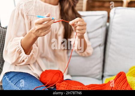 Giovane ispanica che tesse in finisce a casa Foto Stock