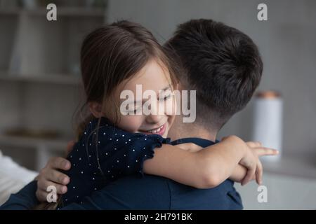 Figlia che coccola strettamente il suo amato papà, da vicino Foto Stock