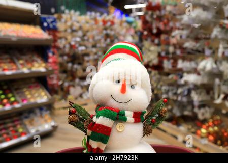 Negozio di inverno di Natale 2022, bella pupazzi di neve divertente in cappelli rossi. I giocattoli e le decorazioni di Capodanno preferiti in negozio. Shopping natalizio durante le feste invernali Foto Stock