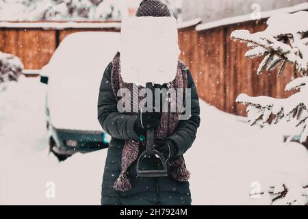 donna con pala che pulisce la neve intorno all'auto. Pala invernale. Rimuovere la neve dopo la bizzarda Foto Stock